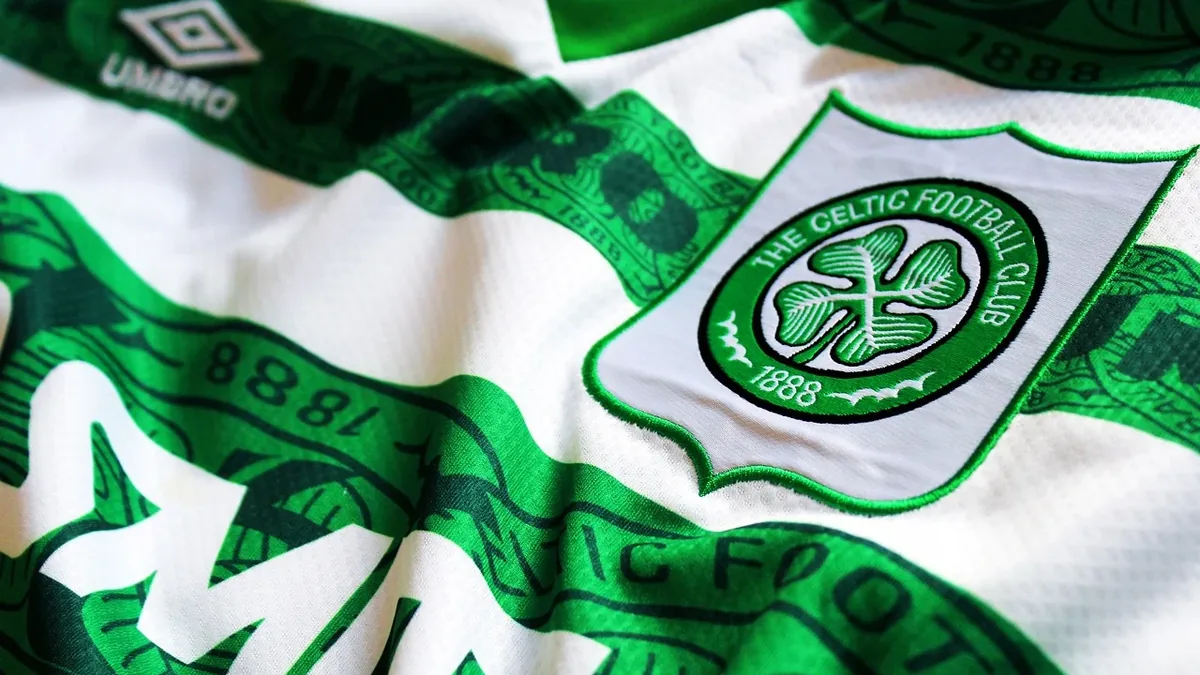A close-up of a white and green Celtic Football Club jersey with the club's logo prominently displayed.