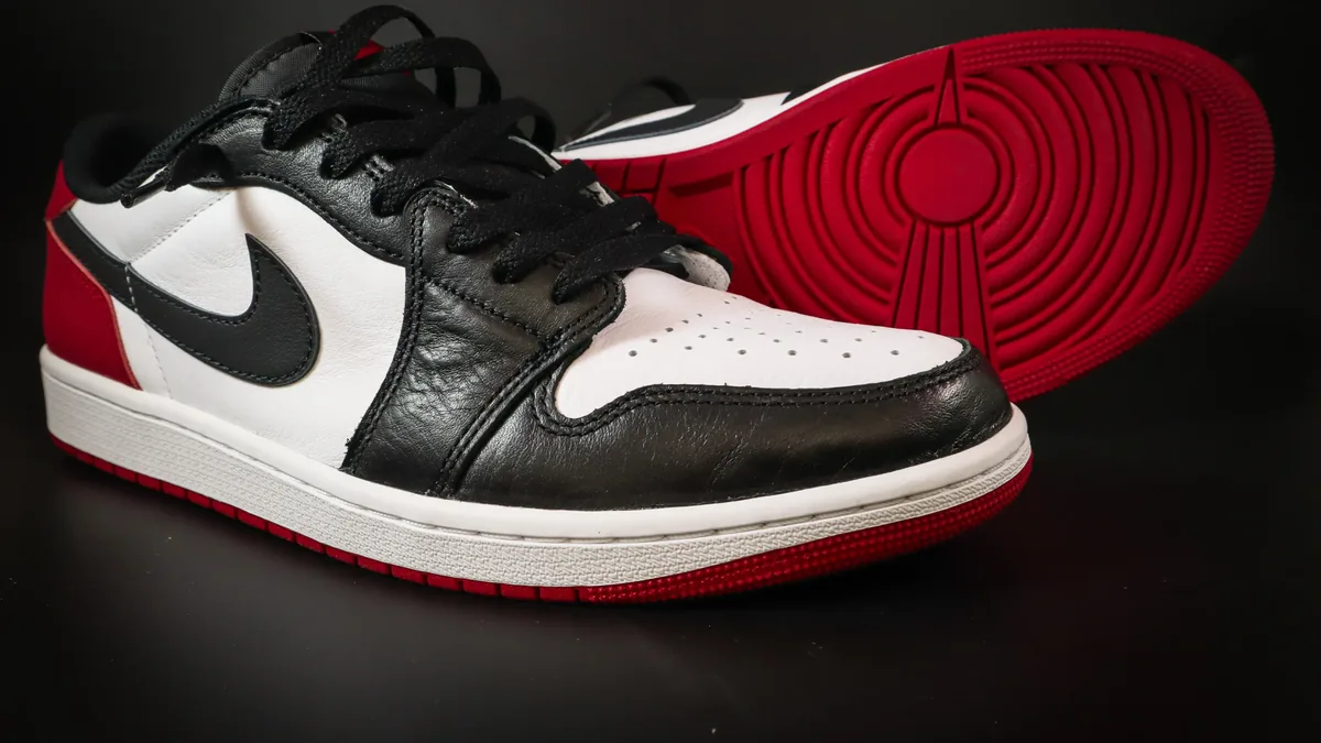 A pair of Nike Air Jordan 1 sneakers, with one shoe lying on its side and the other shoe's sole visible behind it.