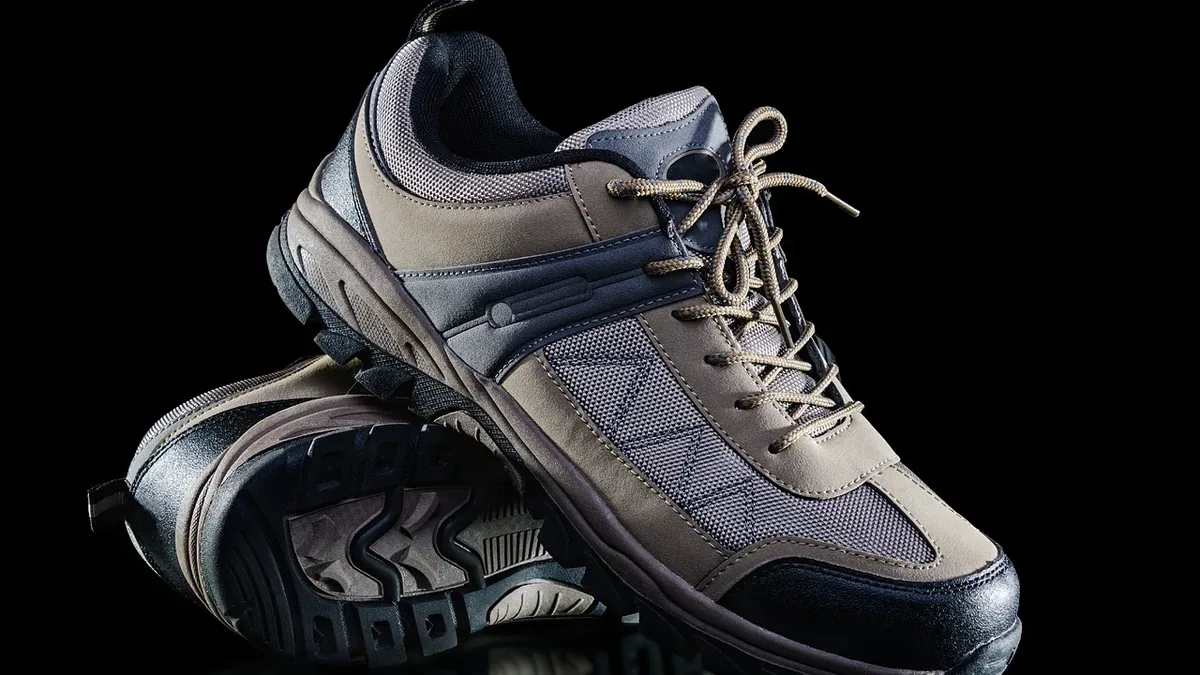 A pair of sneakers with laces, one placed on top of the other, against a black background.